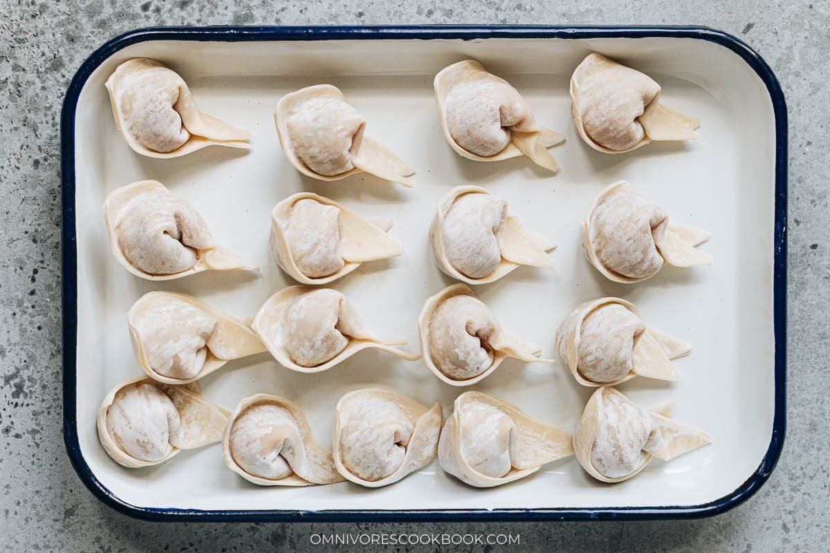 Wrapped wontons resting on a tray in a single layer