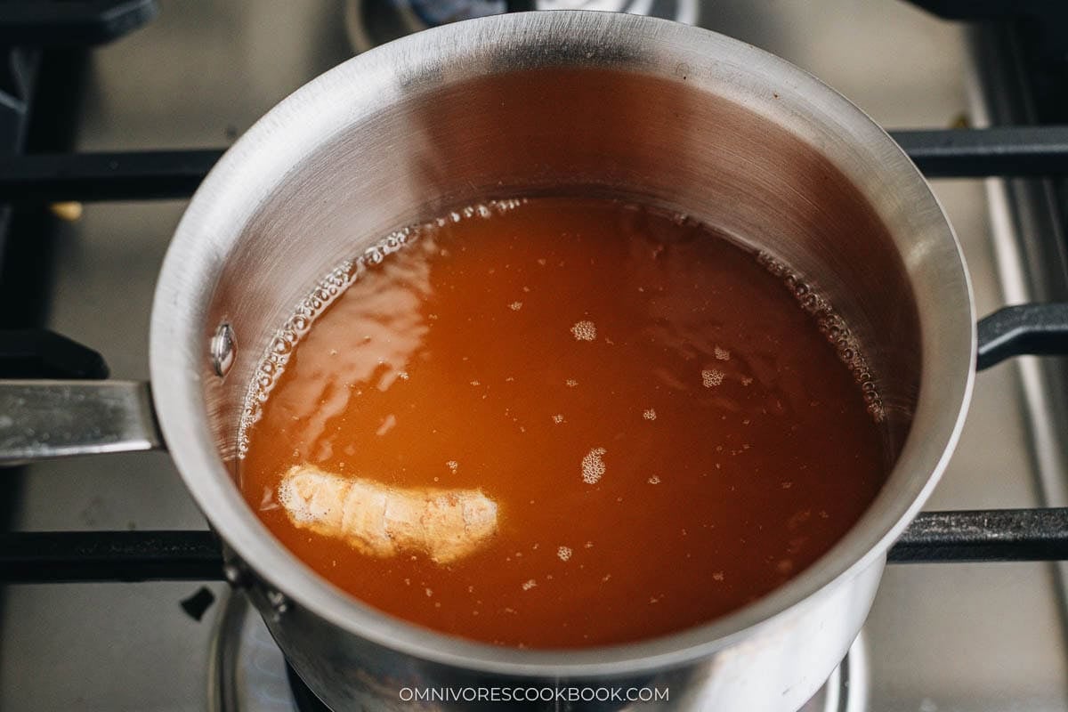Chicken stock and ginger slices simmering in a pot for the wonton soup broth