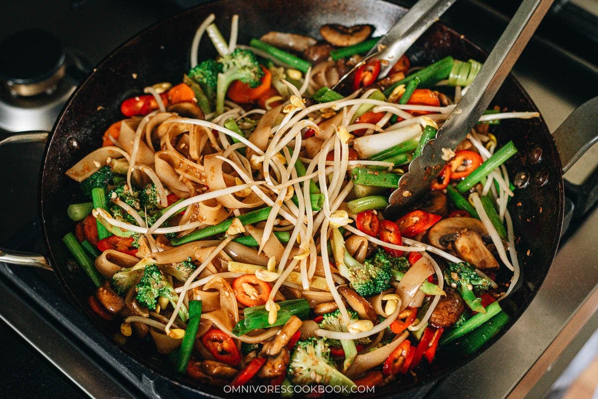 Vegetable chow fun finished with green onion, bean sprouts, and red pepper