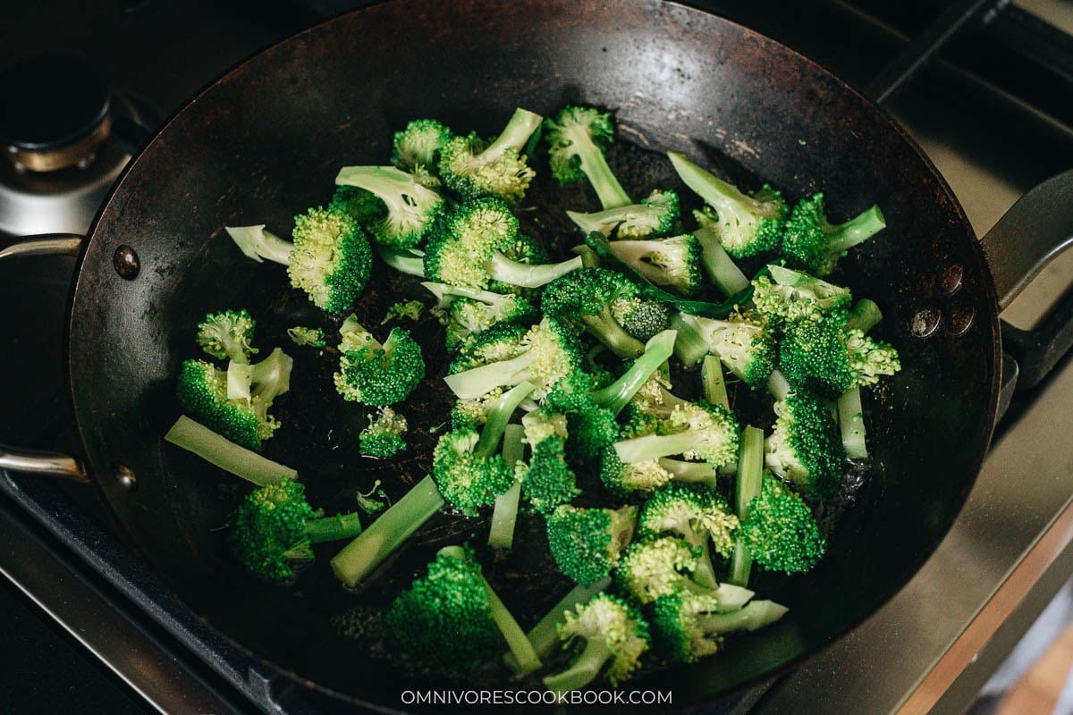 Broccoli florets steaming in a splash of water in a skillet
