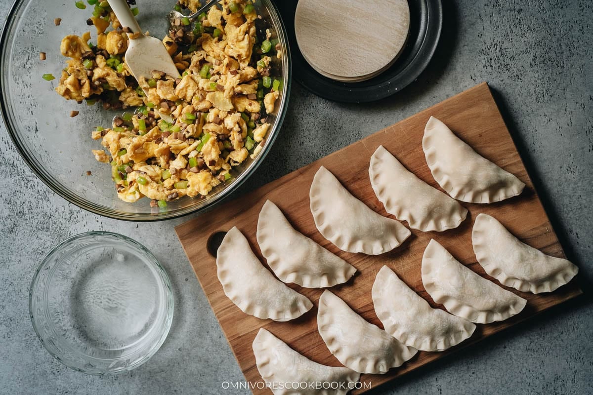 Raw egg and pepper dumplings arranged on a tray for freezing
