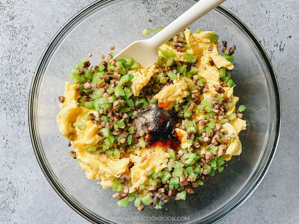 Egg, mushroom, and diced green pepper mixed with seasonings in a bowl