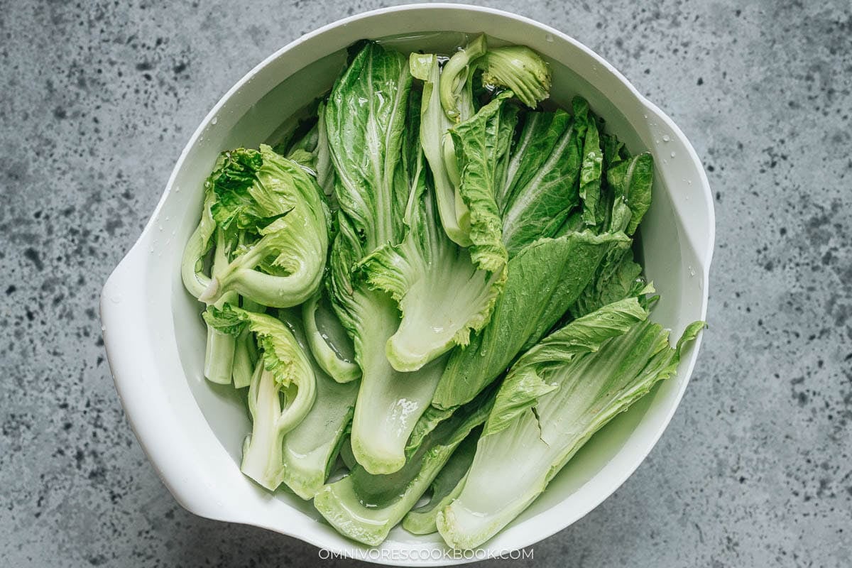 Trimming the tough ends from fresh mustard greens and halving the core before pickling
