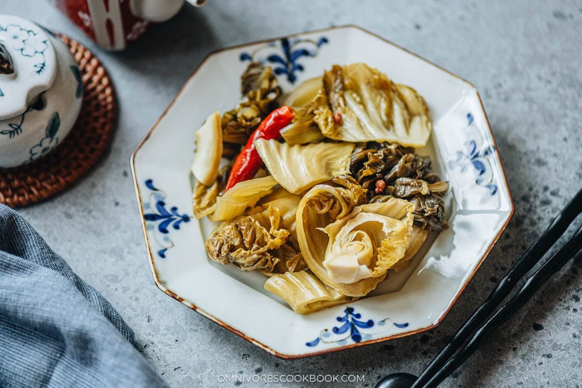 Sichuan pickled mustard greens with ginger, dried chilies, and Sichuan peppercorns on a plate